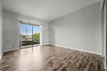 A room with wooden flooring and a sliding glass door leading to a balcony at Lafayette Apartments, Los Angeles